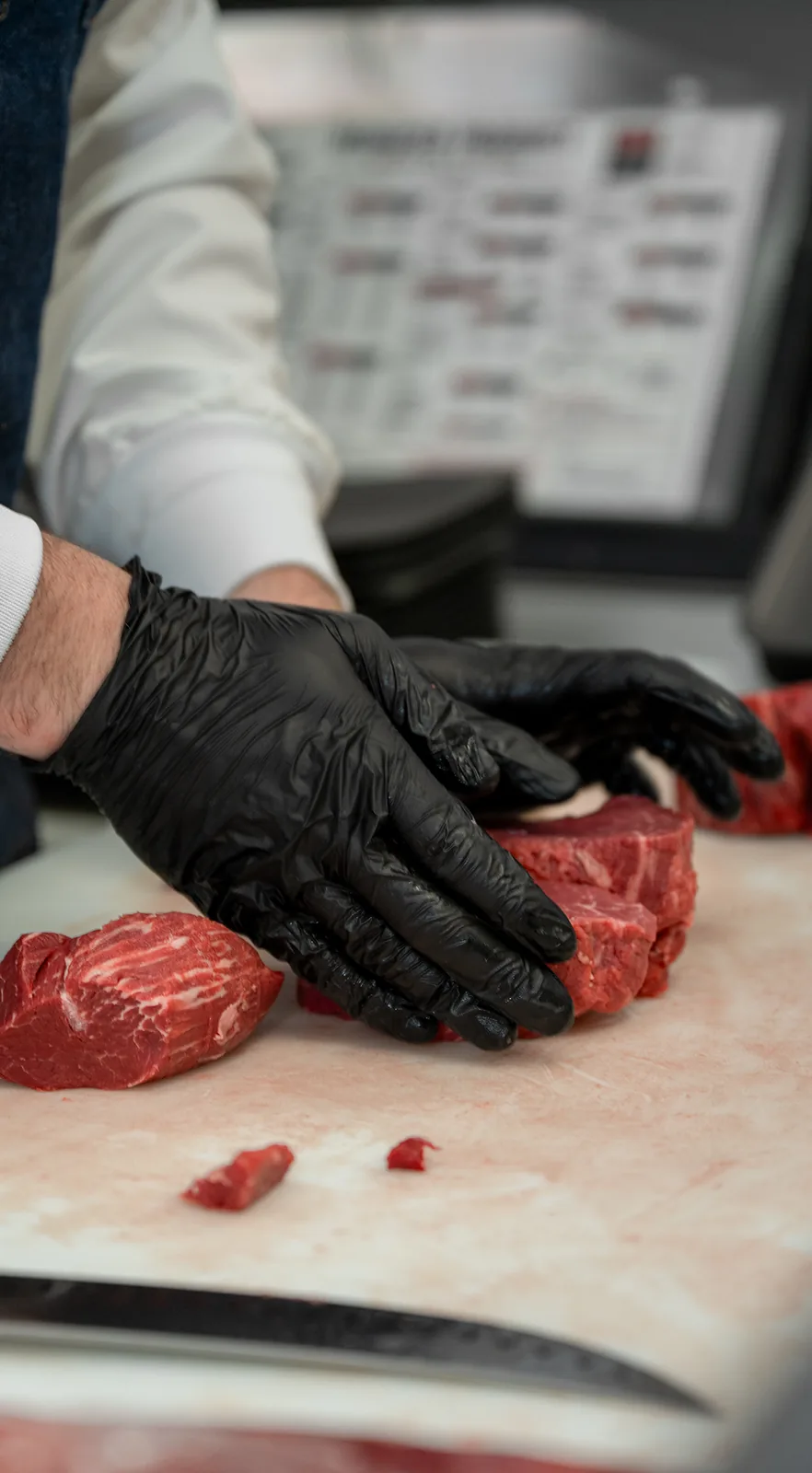 A butcher hand-trimming premium beef