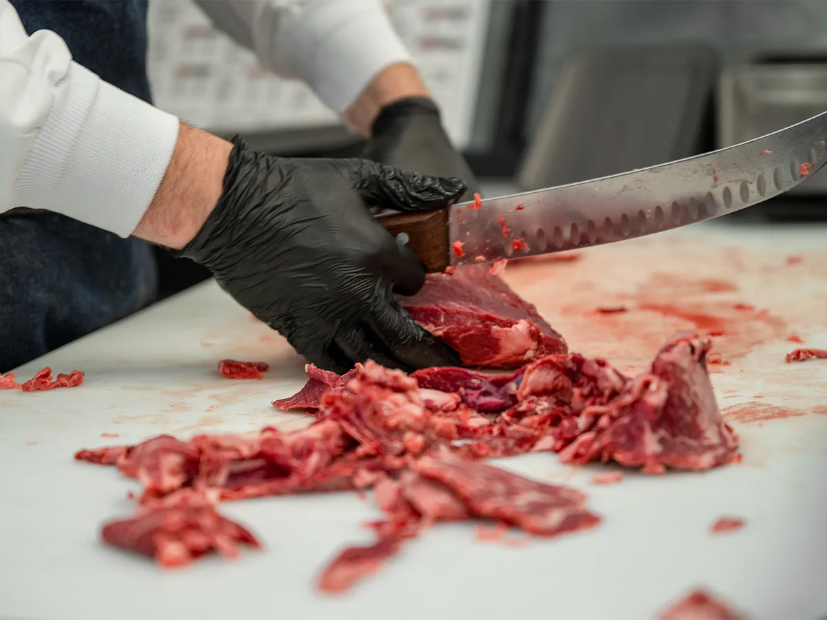 Close-up of a butcher hand-trimming beef